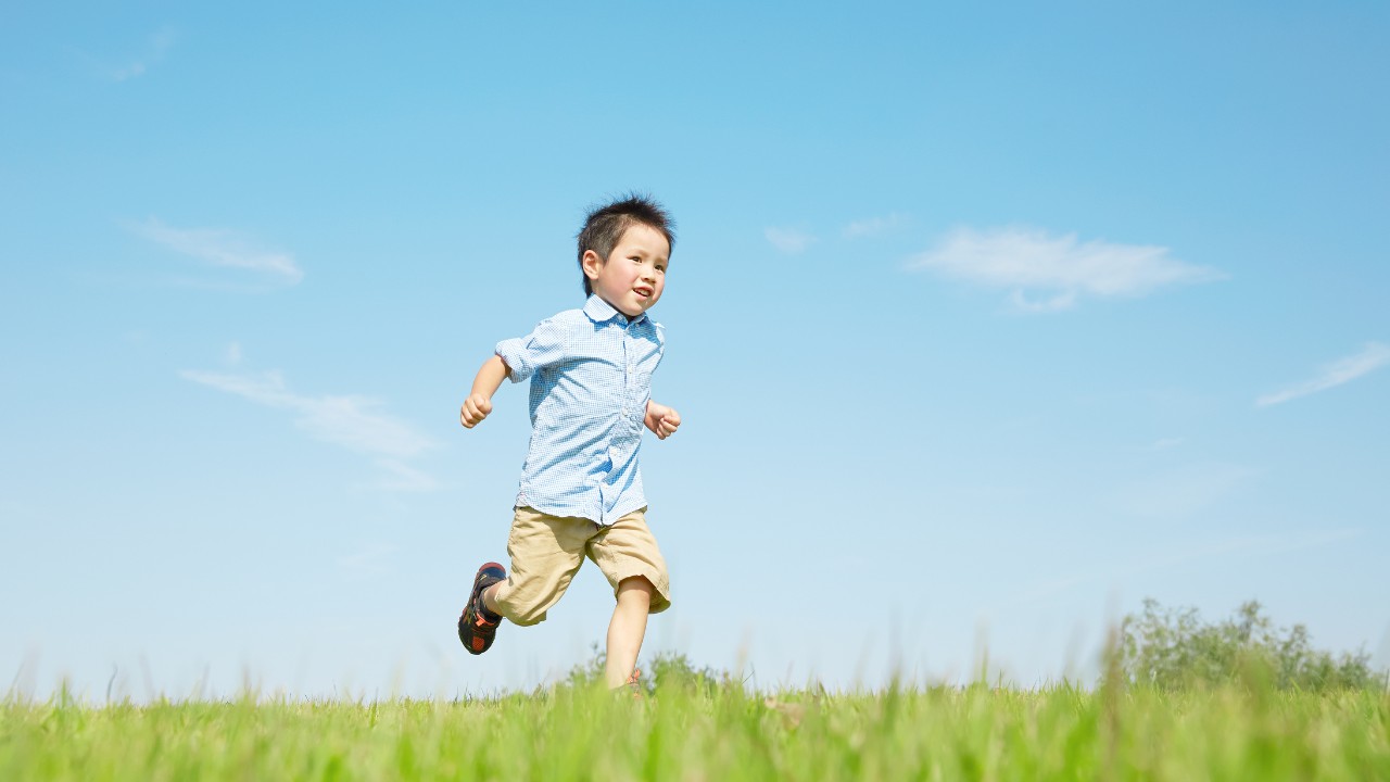 青空の下、芝生を走る男の子